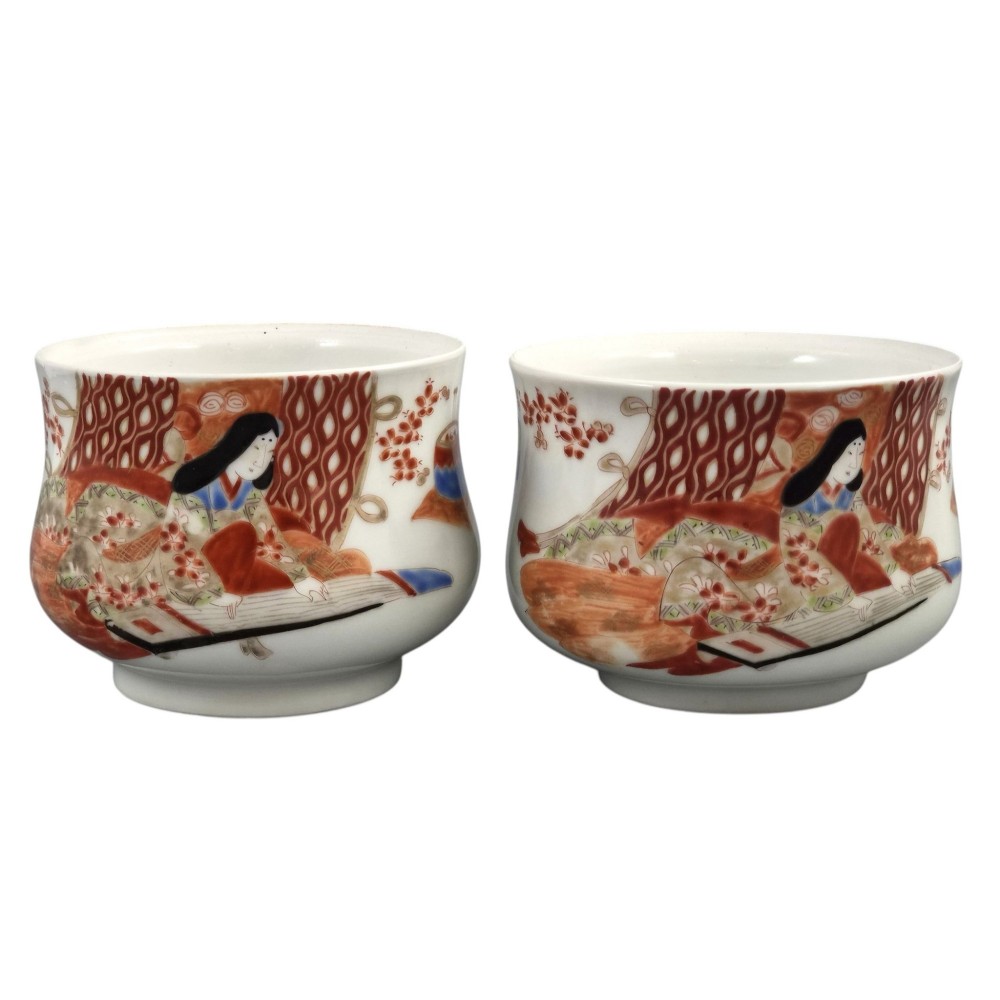 A pair of late 19th-century white Japanese Imari porcelain handleless sencha teacups hand-painted with figures at low desks and floral motifs in iron red and black enamels. View III