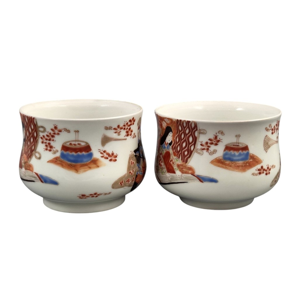 A pair of late 19th-century white Japanese Imari porcelain handleless sencha teacups hand-painted with figures at low desks and floral motifs in iron red and black enamels. View IV