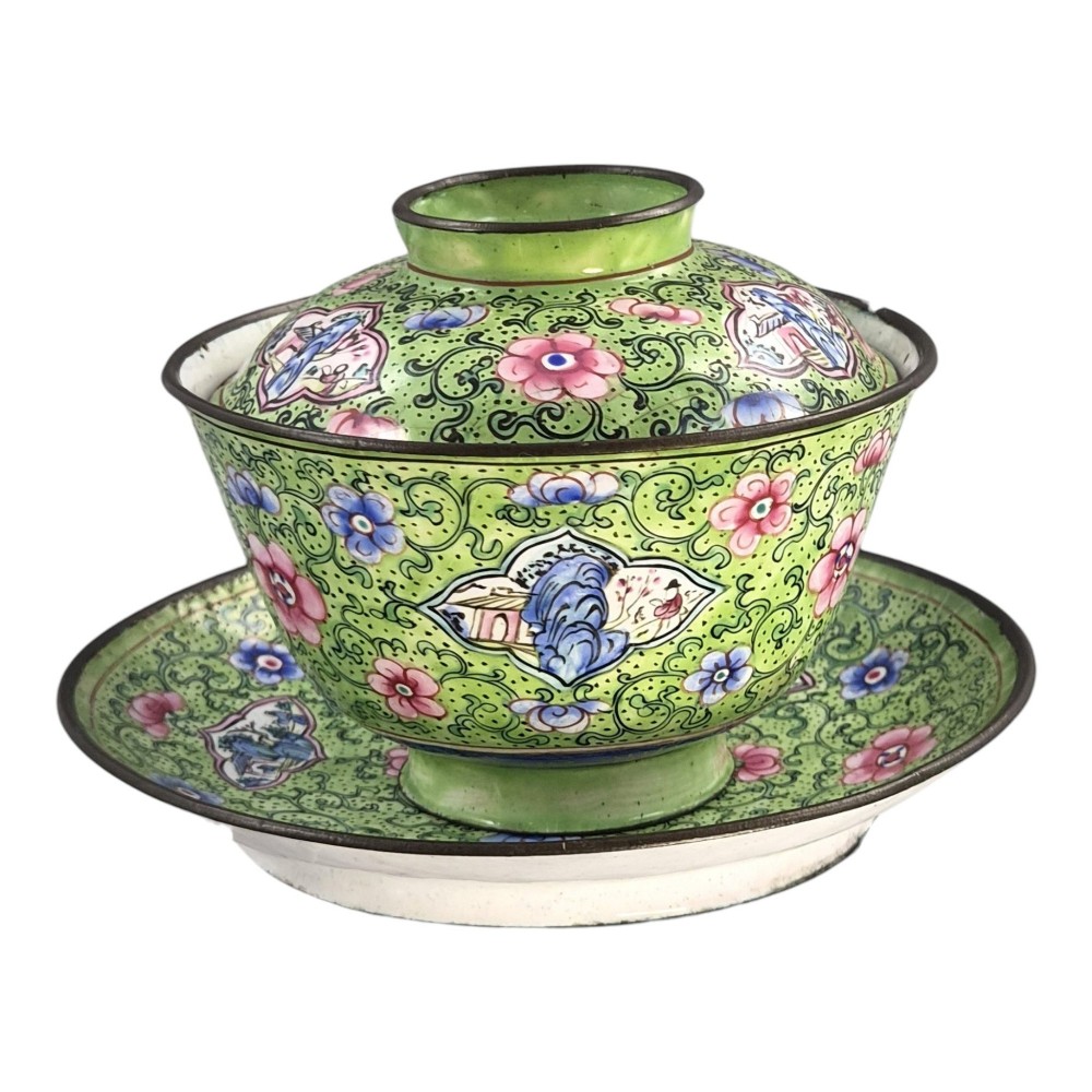 A Chinese Canton enamel gaiwan featuring a green ground with pink floral scrolls and landscape cartouches, complete with lid and matching saucer. View V