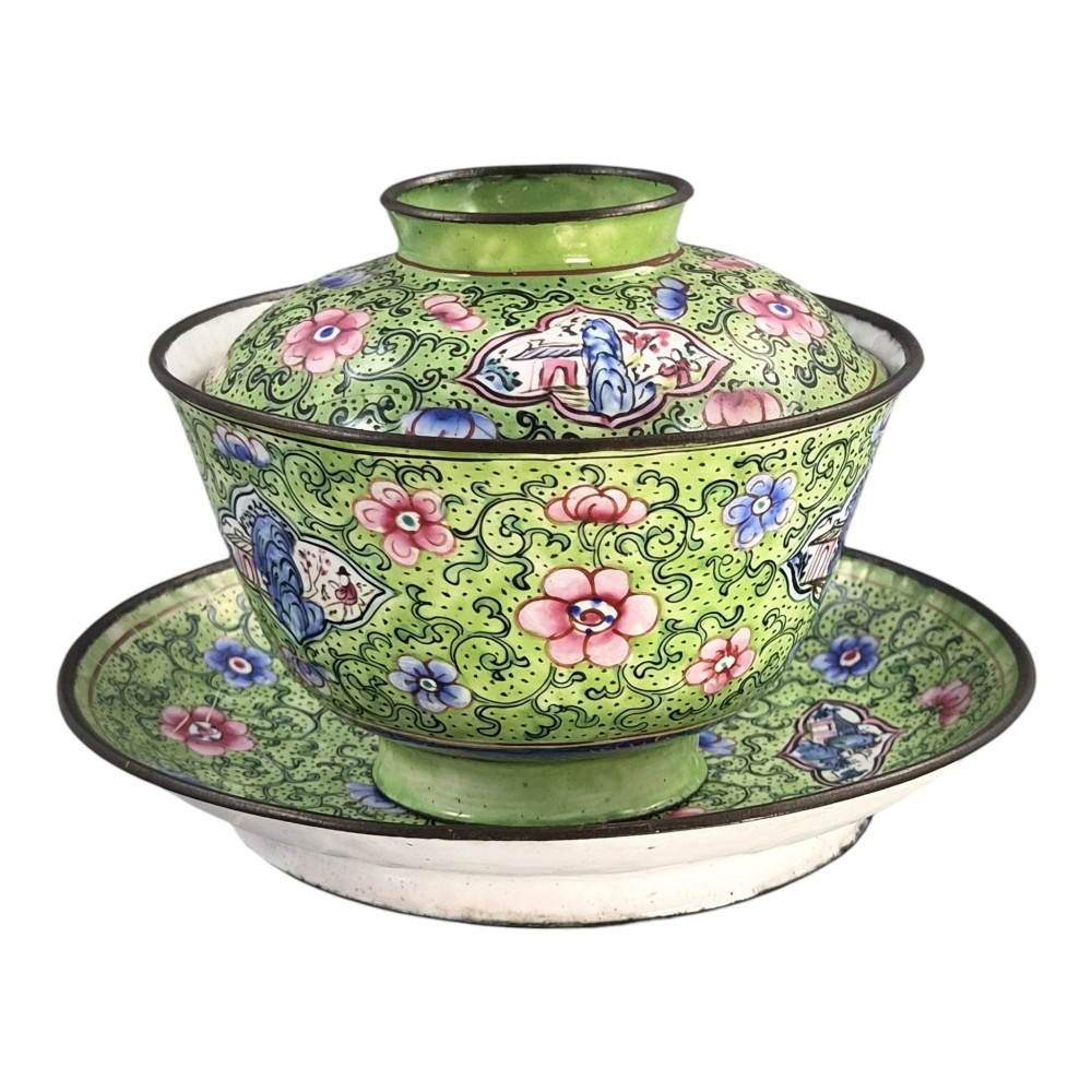 A Chinese Canton enamel gaiwan featuring a green ground with pink floral scrolls and landscape cartouches, complete with lid and matching saucer. View VI