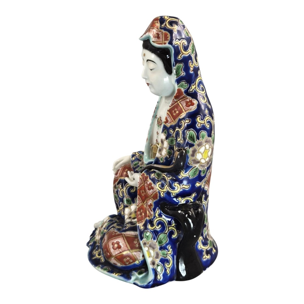 A seated Japanese Arita porcelain figure depicting Jigoku Dayu wearing a patterned blue, red, and gold hooded robe. View II