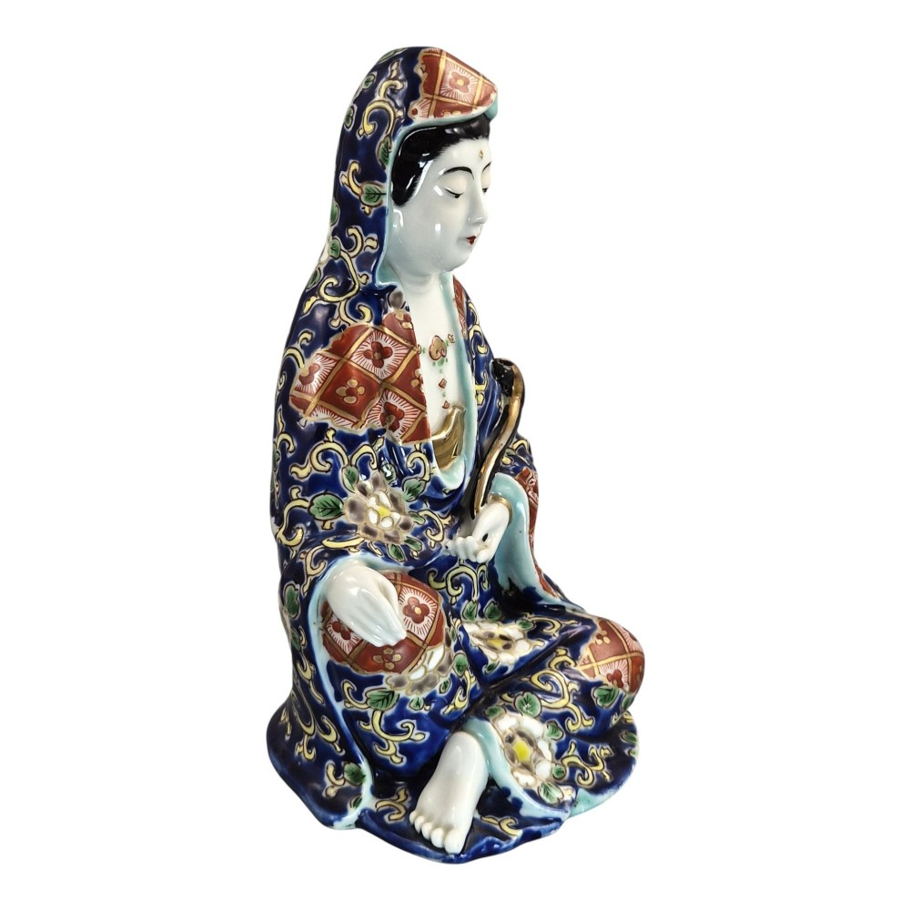 A seated Japanese Arita porcelain figure depicting Jigoku Dayu wearing a patterned blue, red, and gold hooded robe. View VI