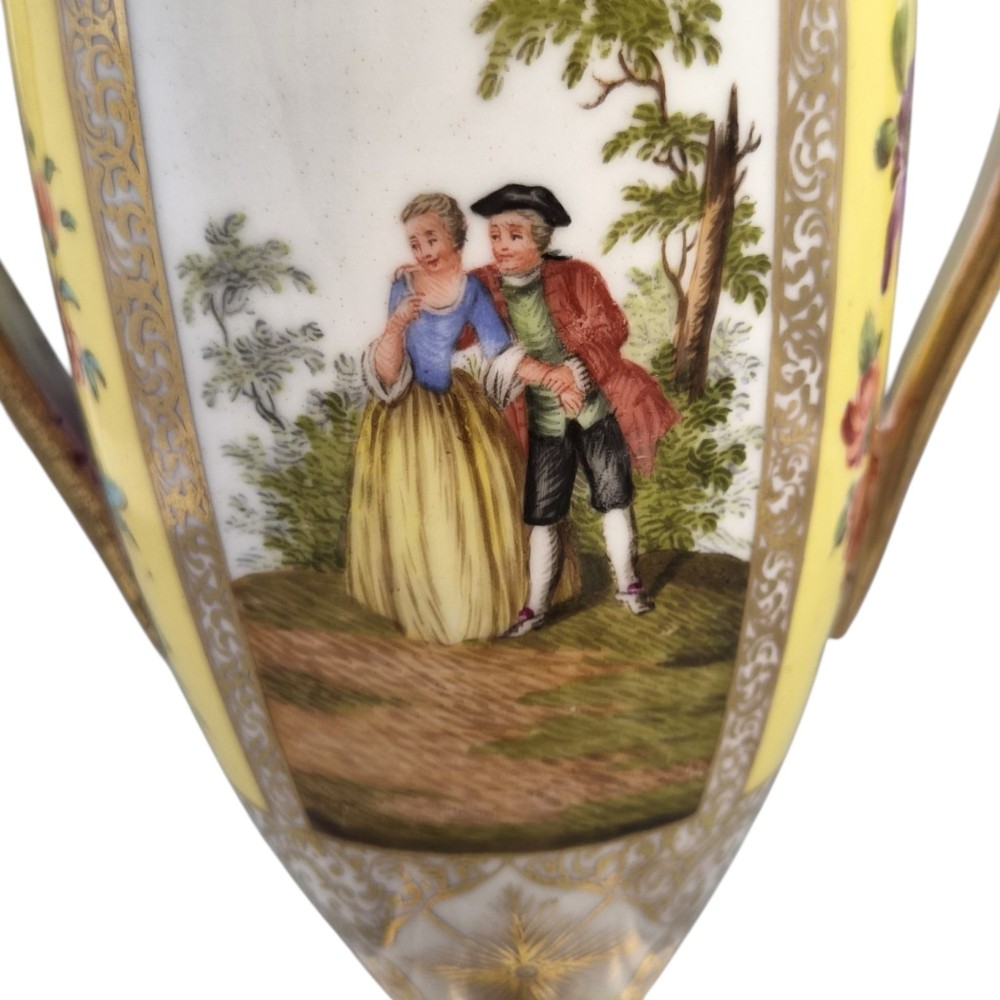 A pair of late nineteenth-century Dresden porcelain urns featuring yellow ground, hand-painted romantic scenes, gilded handles, and square pedestal bases. View X