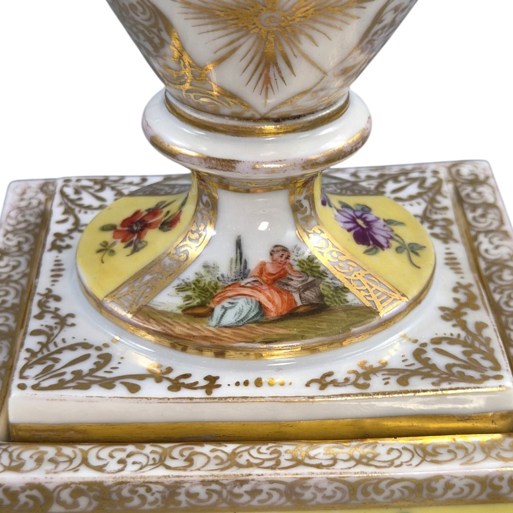 A pair of late nineteenth-century Dresden porcelain urns featuring yellow ground, hand-painted romantic scenes, gilded handles, and square pedestal bases. View XIII