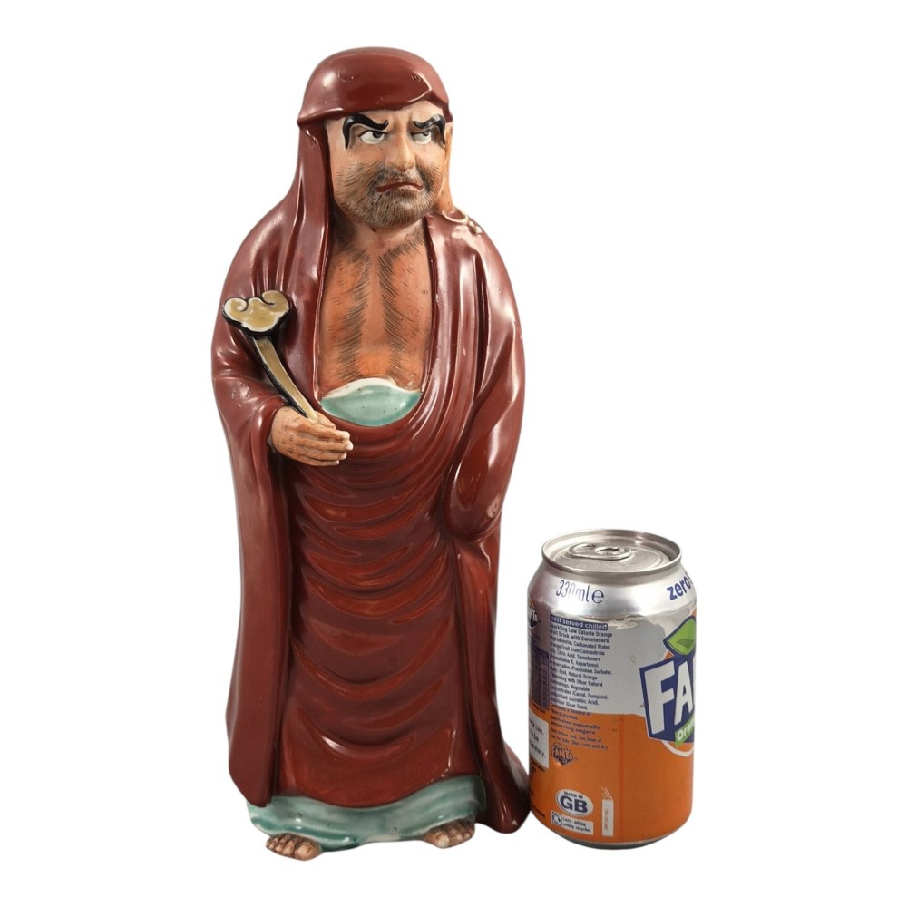 A standing Japanese Kutani porcelain okimono figure depicting Bodhidharma wearing draped terracotta red robes and holding a sceptre. View VIII