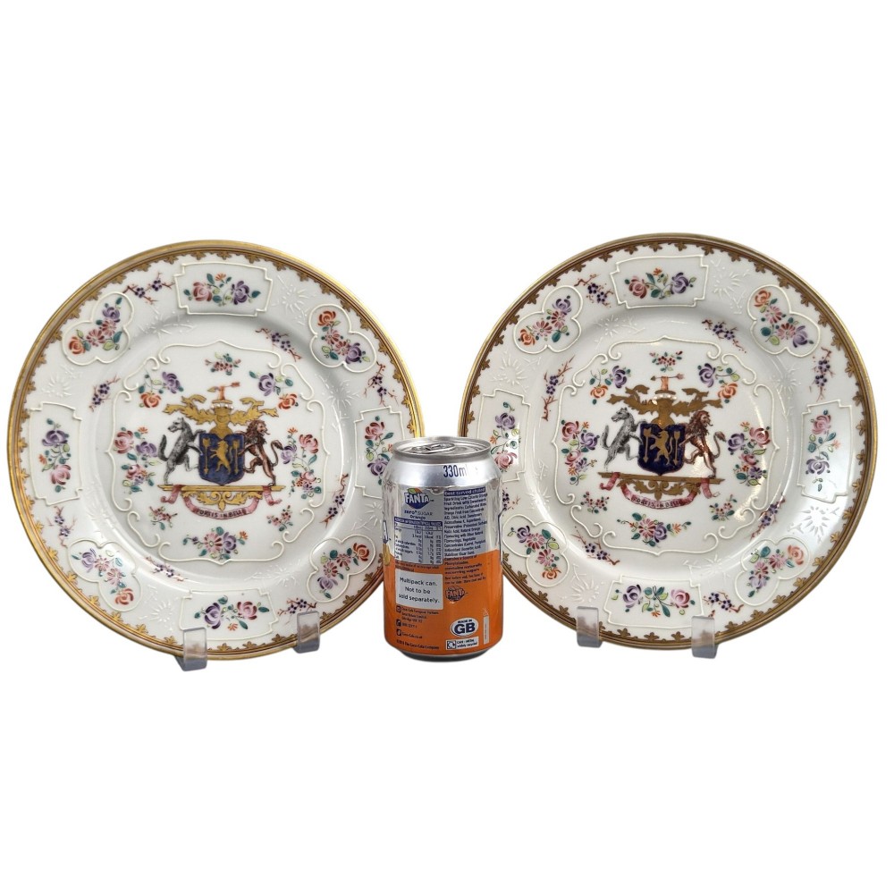 A pair of circular white porcelain plates featuring a central coat of arms, hand-painted floral sprays, raised enamel details, and gilded rims. View X