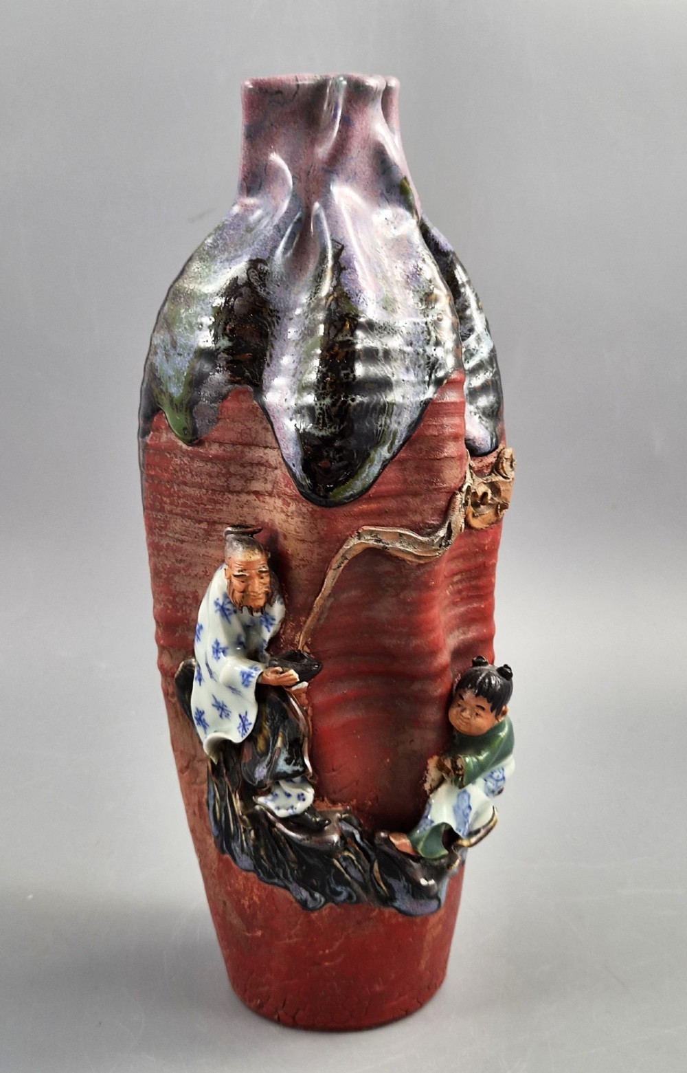 A Japanese Sumida Gawa terracotta vase with applied high-relief figures of a sage and child beneath a dripping lavender and dark flambe glaze.