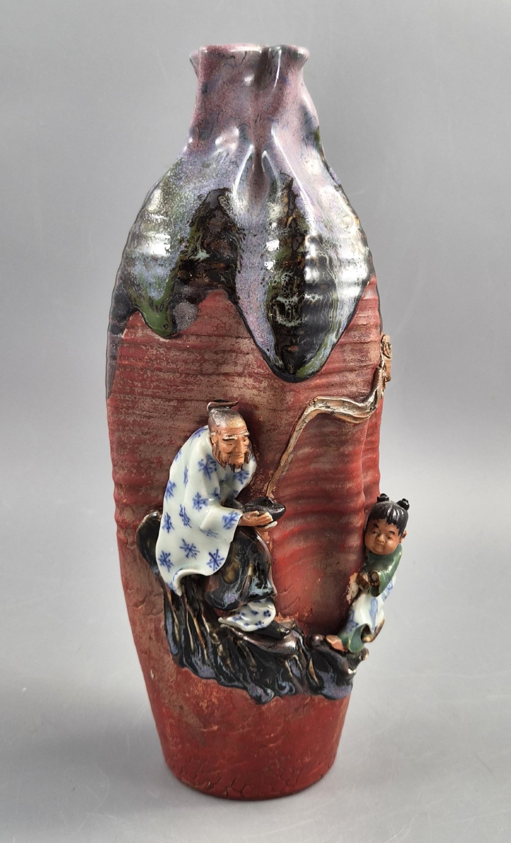 A Japanese Sumida Gawa terracotta vase with applied high-relief figures of a sage and child beneath a dripping lavender and dark flambe glaze. View II