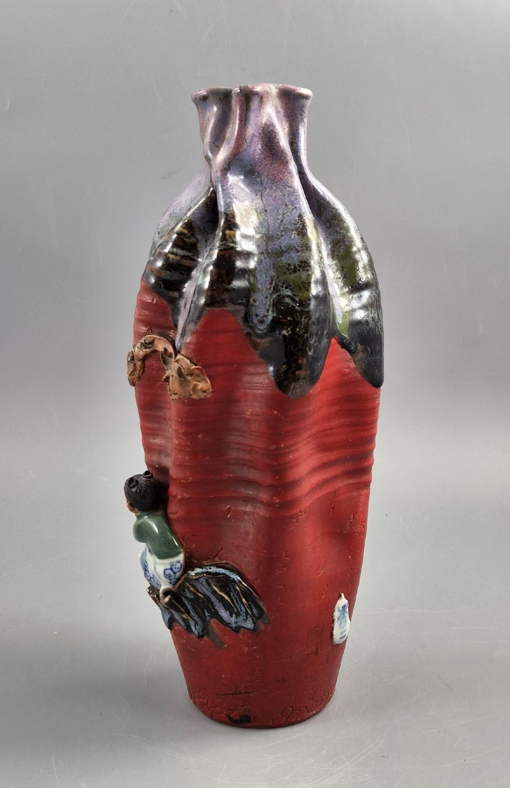 A Japanese Sumida Gawa terracotta vase with applied high-relief figures of a sage and child beneath a dripping lavender and dark flambe glaze. View IV