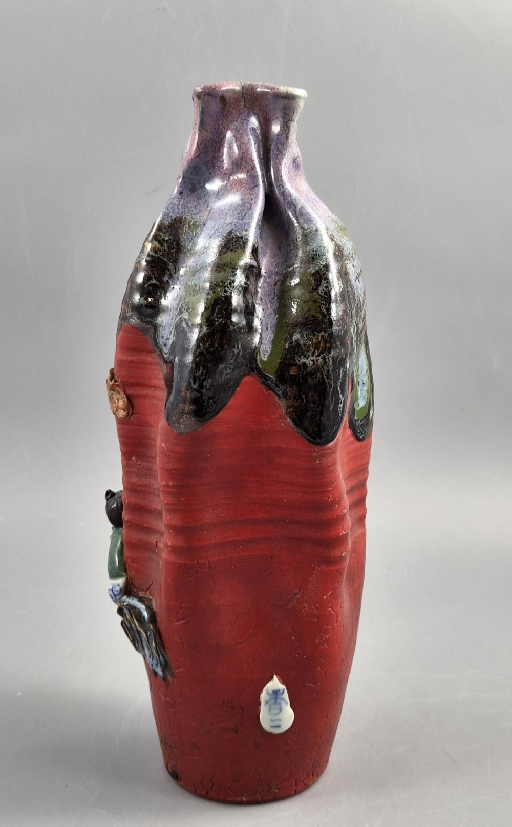 A Japanese Sumida Gawa terracotta vase with applied high-relief figures of a sage and child beneath a dripping lavender and dark flambe glaze. View V