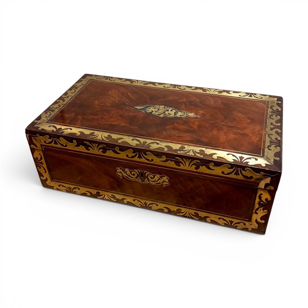 A rectangular dark mahogany writing slope featuring ornate brass scroll inlay around the borders and lid.