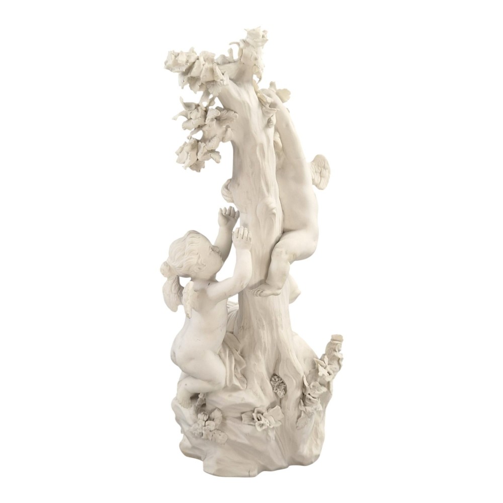 An unglazed off-white biscuit porcelain figure depicting two winged cherubs beside a tree trunk with a birdcage near the base. View III
