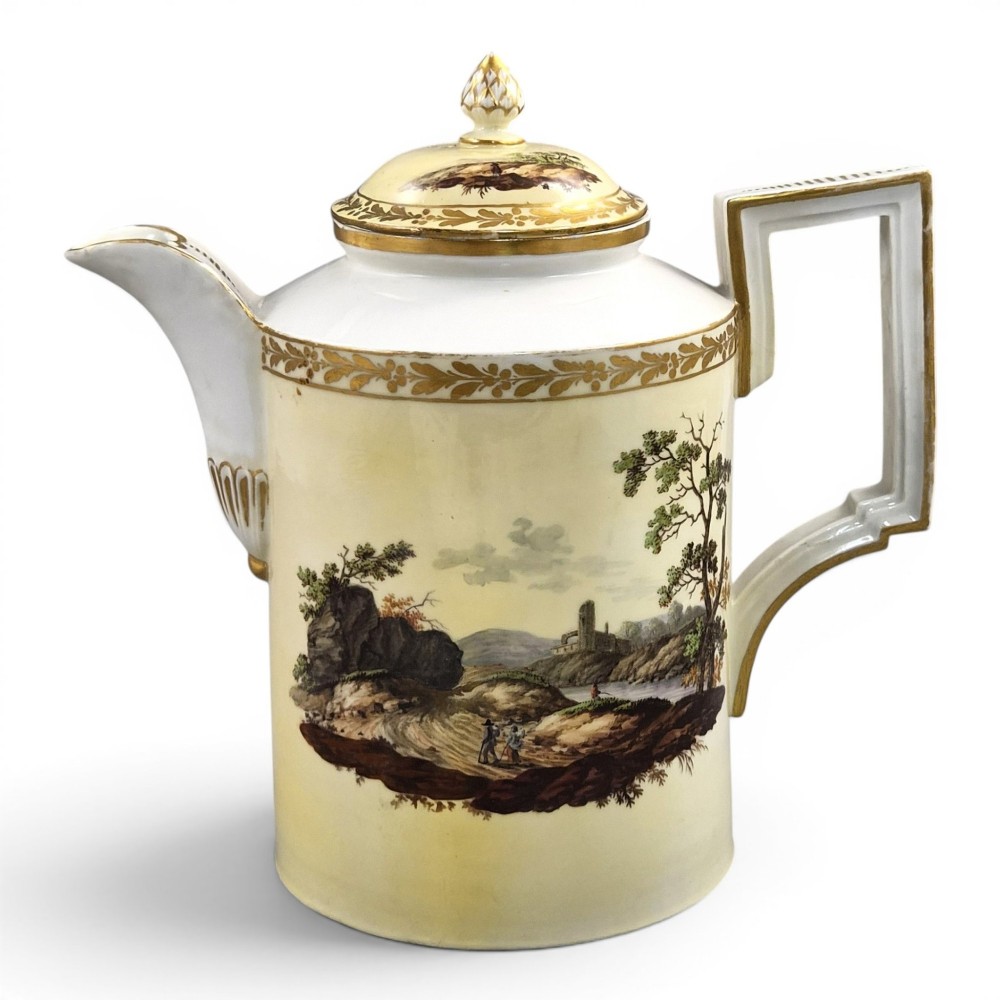 An 18th-century Furstenberg porcelain coffee pot featuring a hand-painted Neoclassical landscape, gold-leaf foliage rim, and an angular gilded handle with a pinecone finial lid.