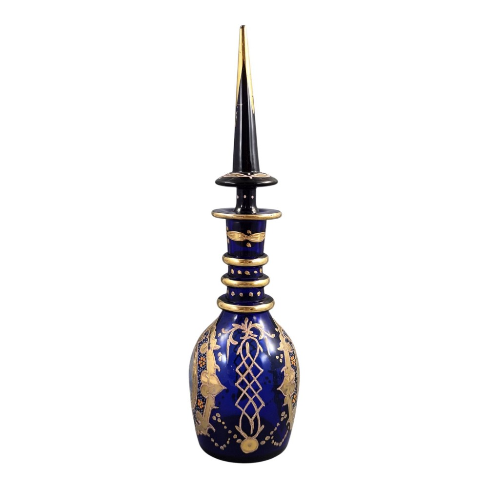 A cobalt blue Bohemian glass decanter decorated with elaborate gold enamelling and a painted portrait medallion, featuring a tall pointed stopper. View II