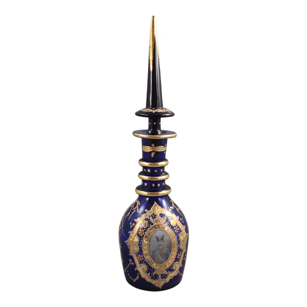 A cobalt blue Bohemian glass decanter decorated with elaborate gold enamelling and a painted portrait medallion, featuring a tall pointed stopper. View III