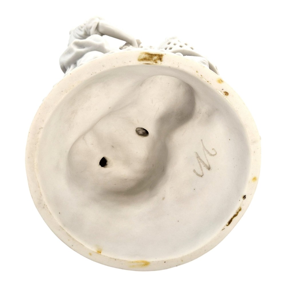 A white matte biscuit porcelain sculptural group depicting three figures and a central urn adorned with delicate floral garlands on a decorative circular base. View II
