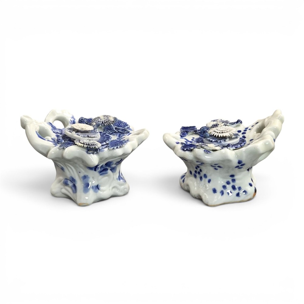 A pair of Japanese Hirado porcelain inkwells featuring fluted bases, underglaze blue decoration, and three-dimensional chrysanthemum motifs on the lids.