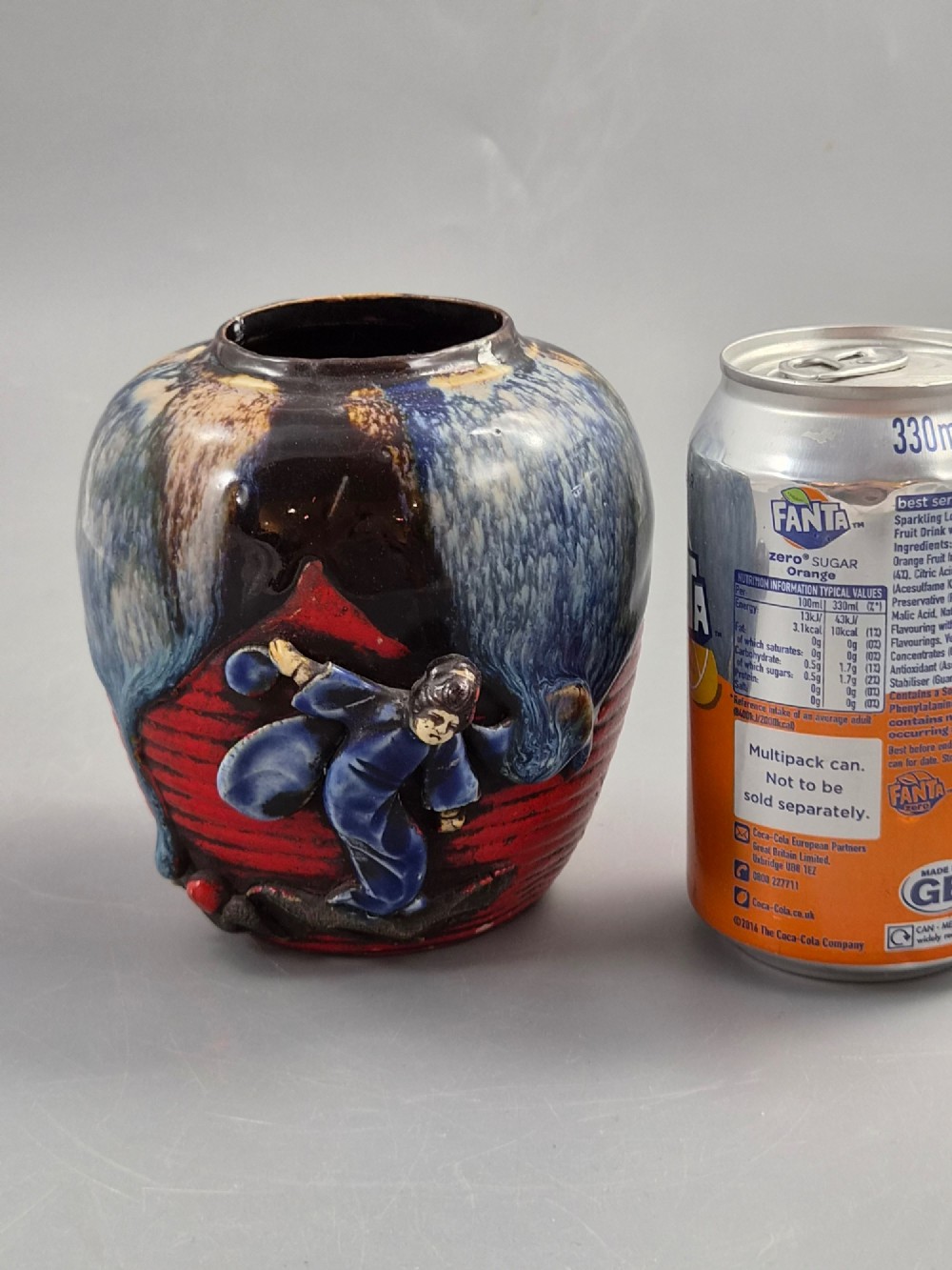 A rounded Japanese Sumida Gawa ceramic jar featuring heavy blue flambe dripping glaze over a ribbed red body with an applied relief climbing figure. View VII