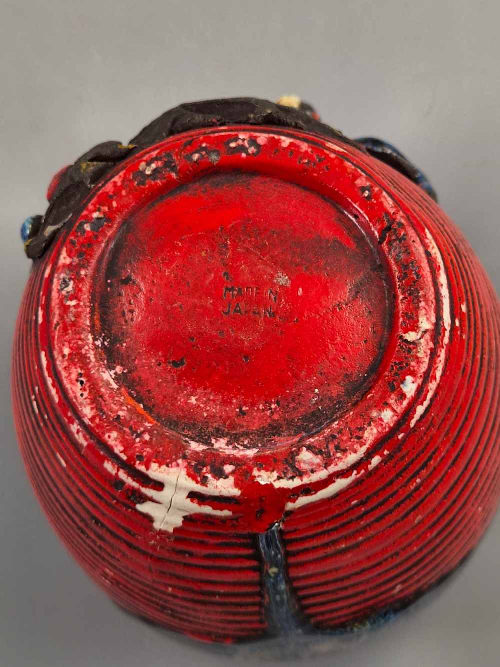 A rounded Japanese Sumida Gawa ceramic jar featuring heavy blue flambe dripping glaze over a ribbed red body with an applied relief climbing figure. View IX