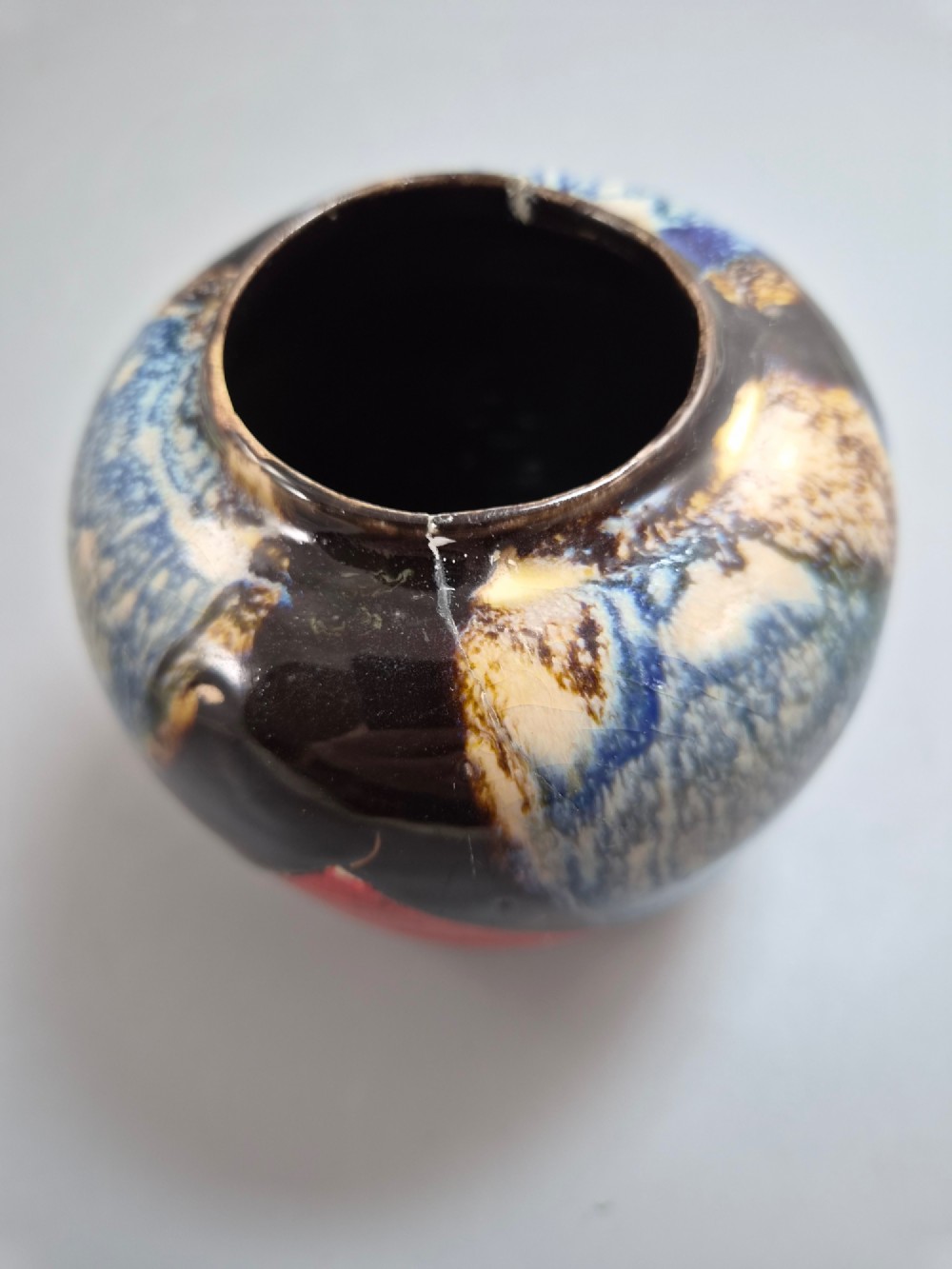 A rounded Japanese Sumida Gawa ceramic jar featuring heavy blue flambe dripping glaze over a ribbed red body with an applied relief climbing figure. View XII