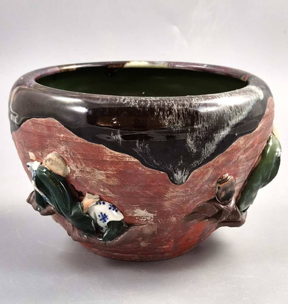An antique Japanese Sumida Gawa ceramic bowl featuring heavy dark flambe glaze over a red terracotta body adorned with three-dimensional applied figures in relief. View V