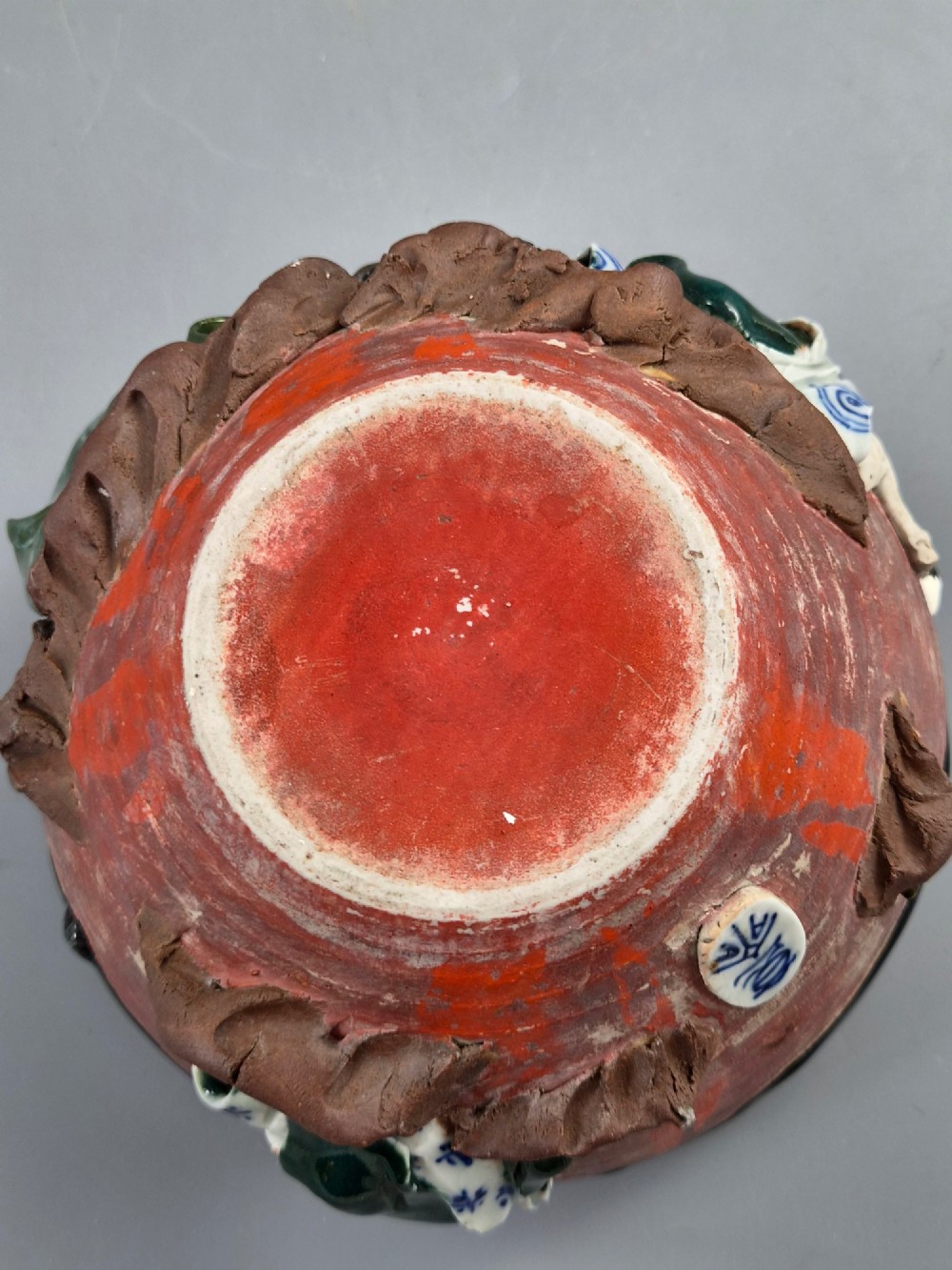 An antique Japanese Sumida Gawa ceramic bowl featuring heavy dark flambe glaze over a red terracotta body adorned with three-dimensional applied figures in relief. View X