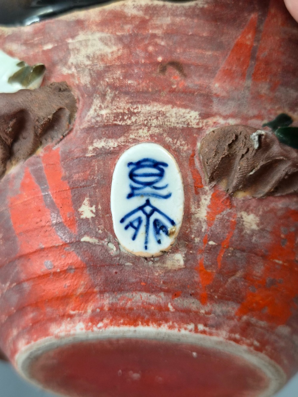An antique Japanese Sumida Gawa ceramic bowl featuring heavy dark flambe glaze over a red terracotta body adorned with three-dimensional applied figures in relief. View XI