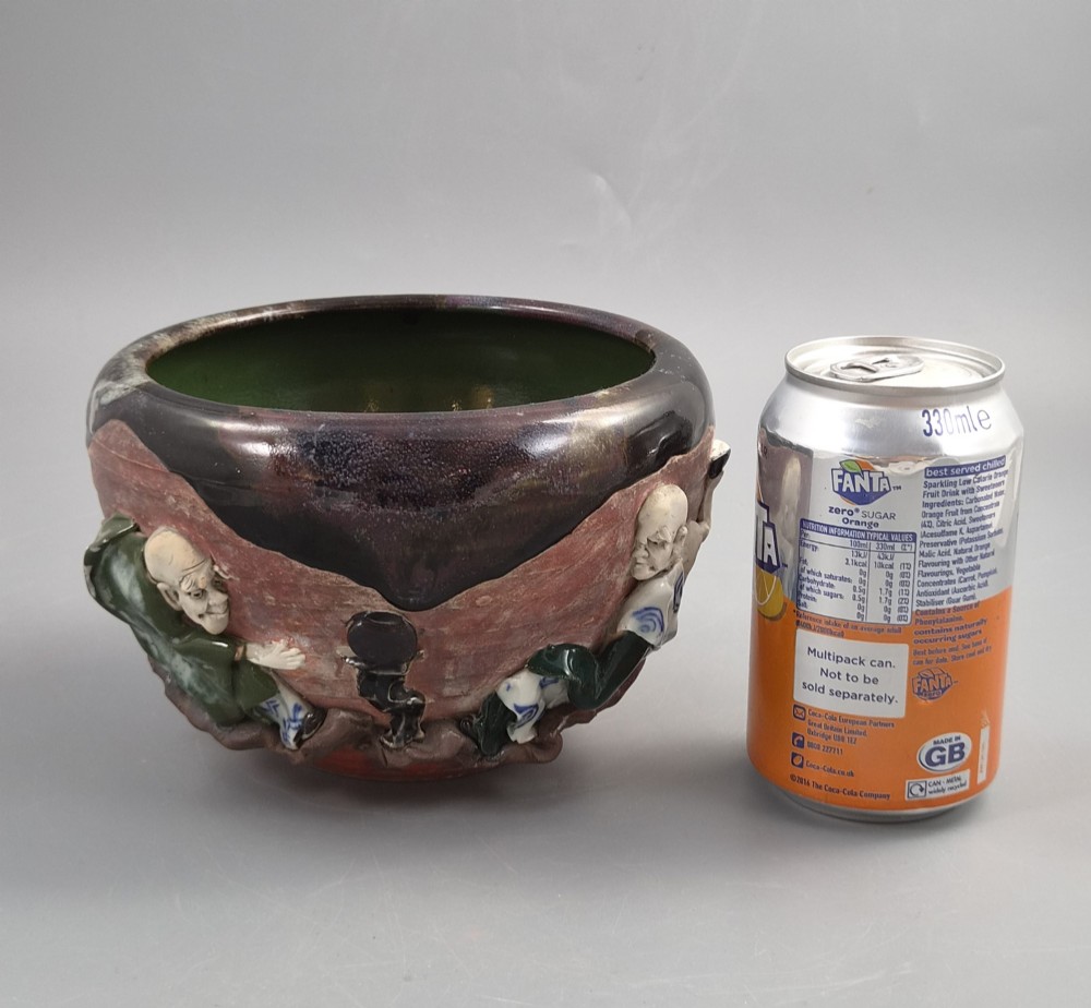 An antique Japanese Sumida Gawa ceramic bowl featuring heavy dark flambe glaze over a red terracotta body adorned with three-dimensional applied figures in relief. View XII