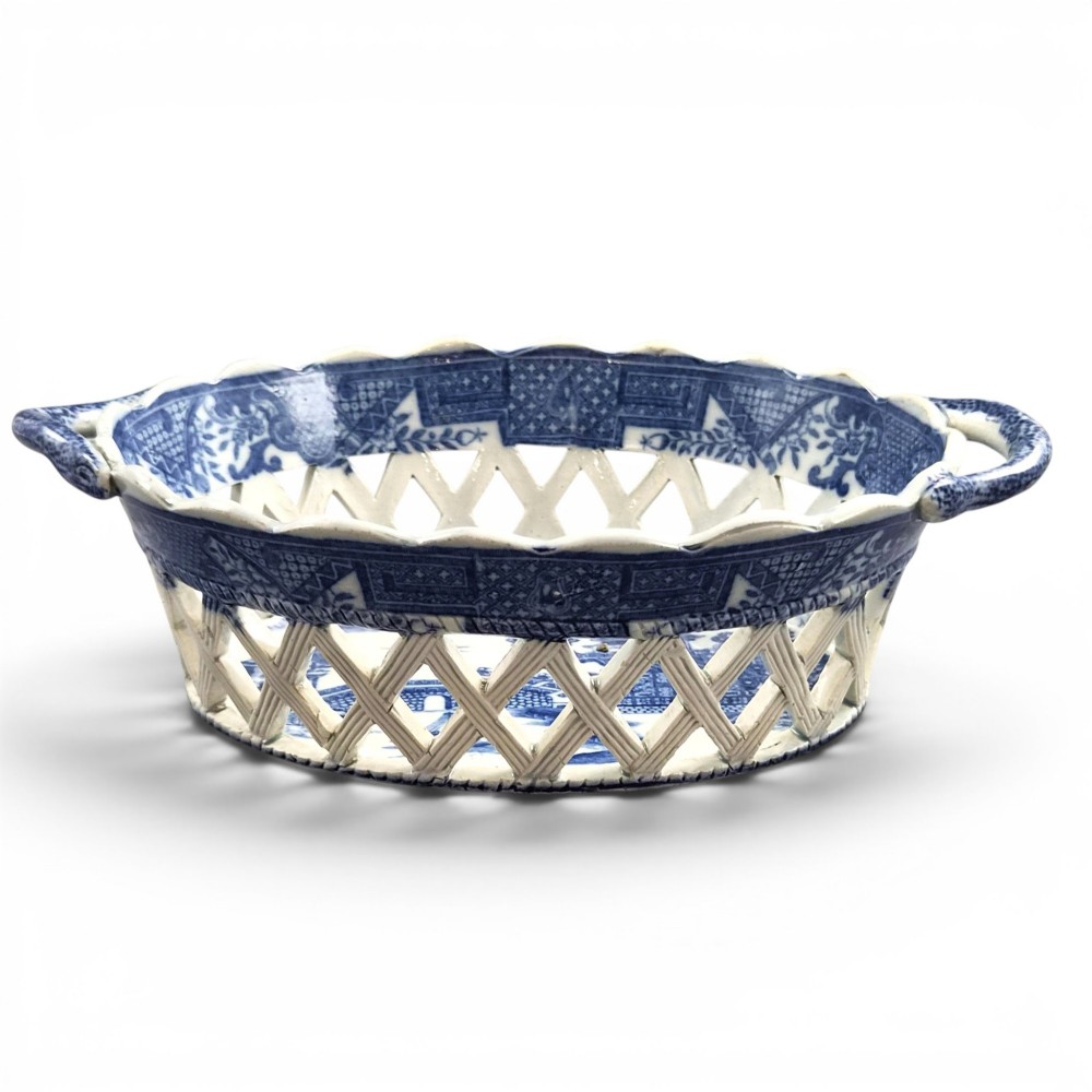 A Regency period blue and white transfer-printed ceramic chestnut basket featuring openwork reticulated lattice sides and two loop side handles.