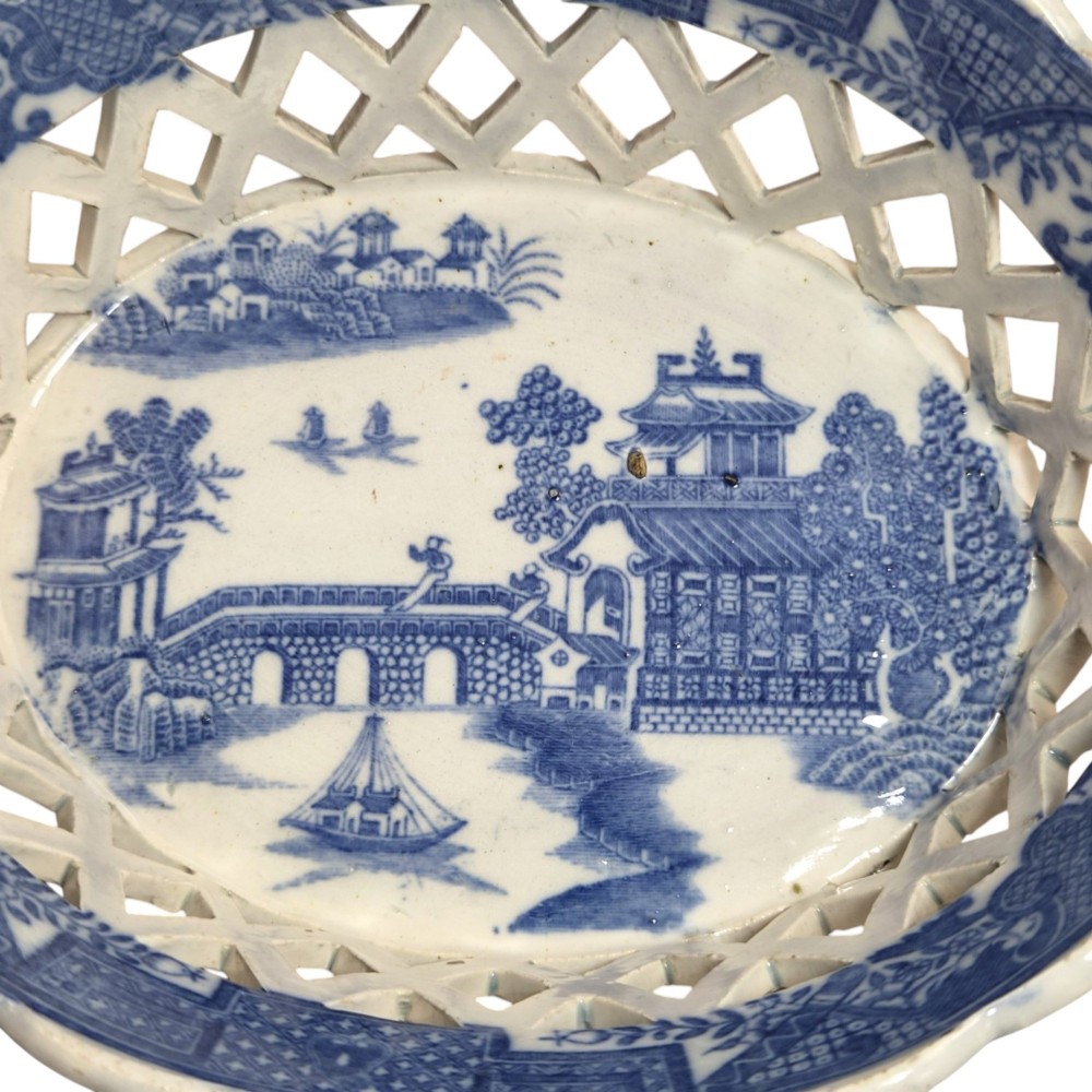 A Regency period blue and white transfer-printed ceramic chestnut basket featuring openwork reticulated lattice sides and two loop side handles. View X