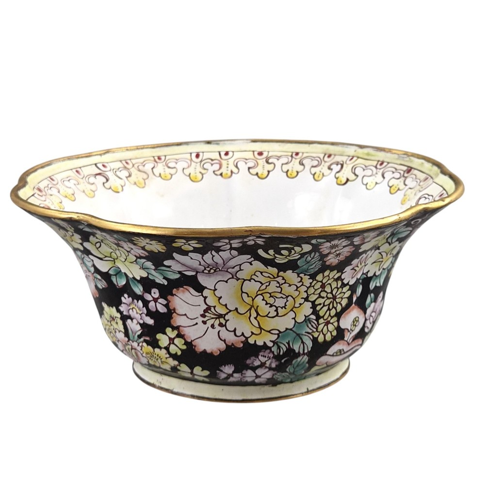 A Chinese Canton enamel-on-copper bowl featuring a lobed rim, a black ground exterior decorated with colourful floral motifs, and a white interior with a patterned border. View V