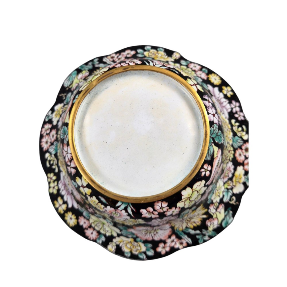 A Chinese Canton enamel-on-copper bowl featuring a lobed rim, a black ground exterior decorated with colourful floral motifs, and a white interior with a patterned border. View VIII