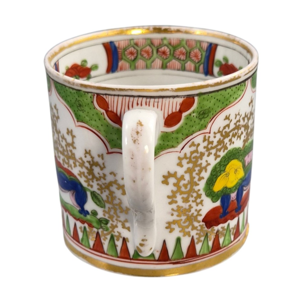 A Regency period Worcester porcelain coffee cup and matching saucer decorated in the hand-painted Dragon in Compartments pattern with green, red, blue, and gilt detailing. View V