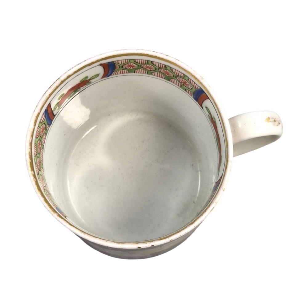 A Regency period Worcester porcelain coffee cup and matching saucer decorated in the hand-painted Dragon in Compartments pattern with green, red, blue, and gilt detailing. View IX