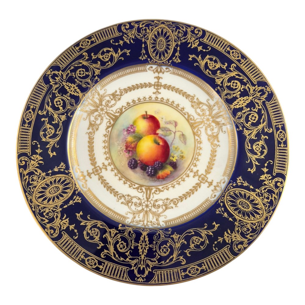 A circular Royal Worcester porcelain cabinet plate featuring a cobalt blue rim with detailed gold gilding framing a central painted still life of apples and berries. View IX