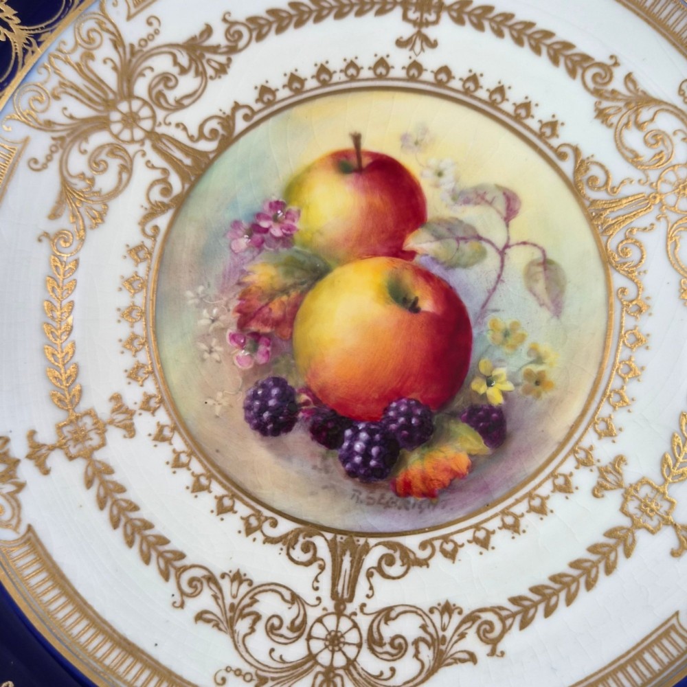 A circular Royal Worcester porcelain cabinet plate featuring a cobalt blue rim with detailed gold gilding framing a central painted still life of apples and berries. View X