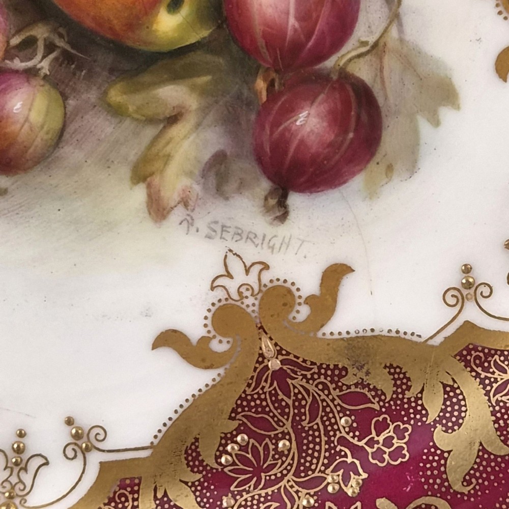 A circular porcelain cabinet plate featuring a central hand-painted fruit still life surrounded by a heavily gilded burgundy rim with scalloped edges. View III