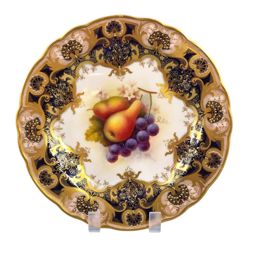 A circular porcelain cabinet plate featuring hand-painted pears and grapes in the centre, framed by an ornate cobalt blue and gold leaf scrollwork border. View II