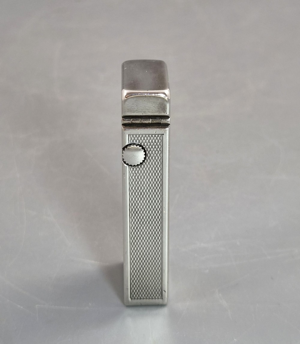 A silver-toned Dunhill Rollagas lighter shown alongside its original paper instruction booklet and red leatherette presentation case. View IV