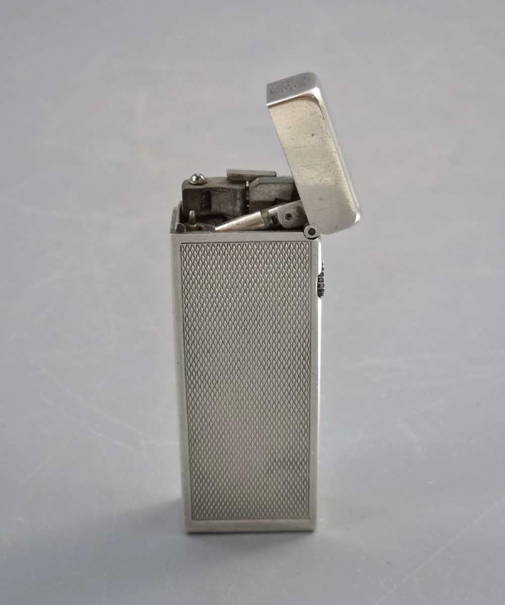 A silver-toned Dunhill Rollagas lighter shown alongside its original paper instruction booklet and red leatherette presentation case. View X