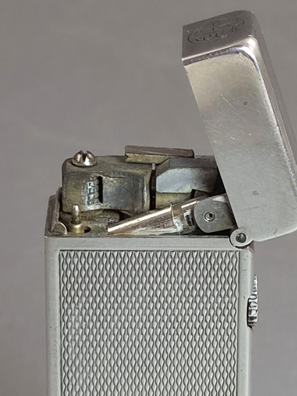 A silver-toned Dunhill Rollagas lighter shown alongside its original paper instruction booklet and red leatherette presentation case. View XII