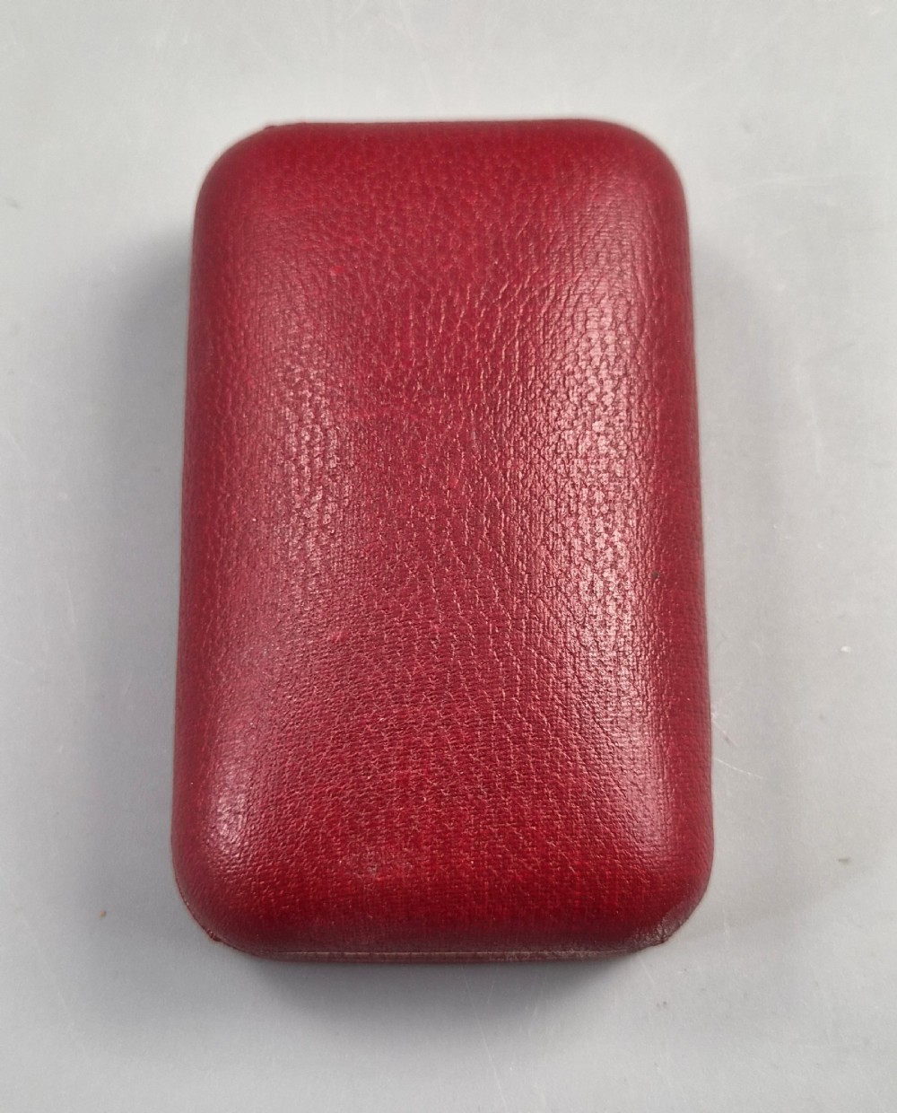 A 1967 gold-plated Dunhill Rollagas pocket lighter with a textured barley pattern, displayed alongside its fitted red presentation case and original printed instruction booklet. View III