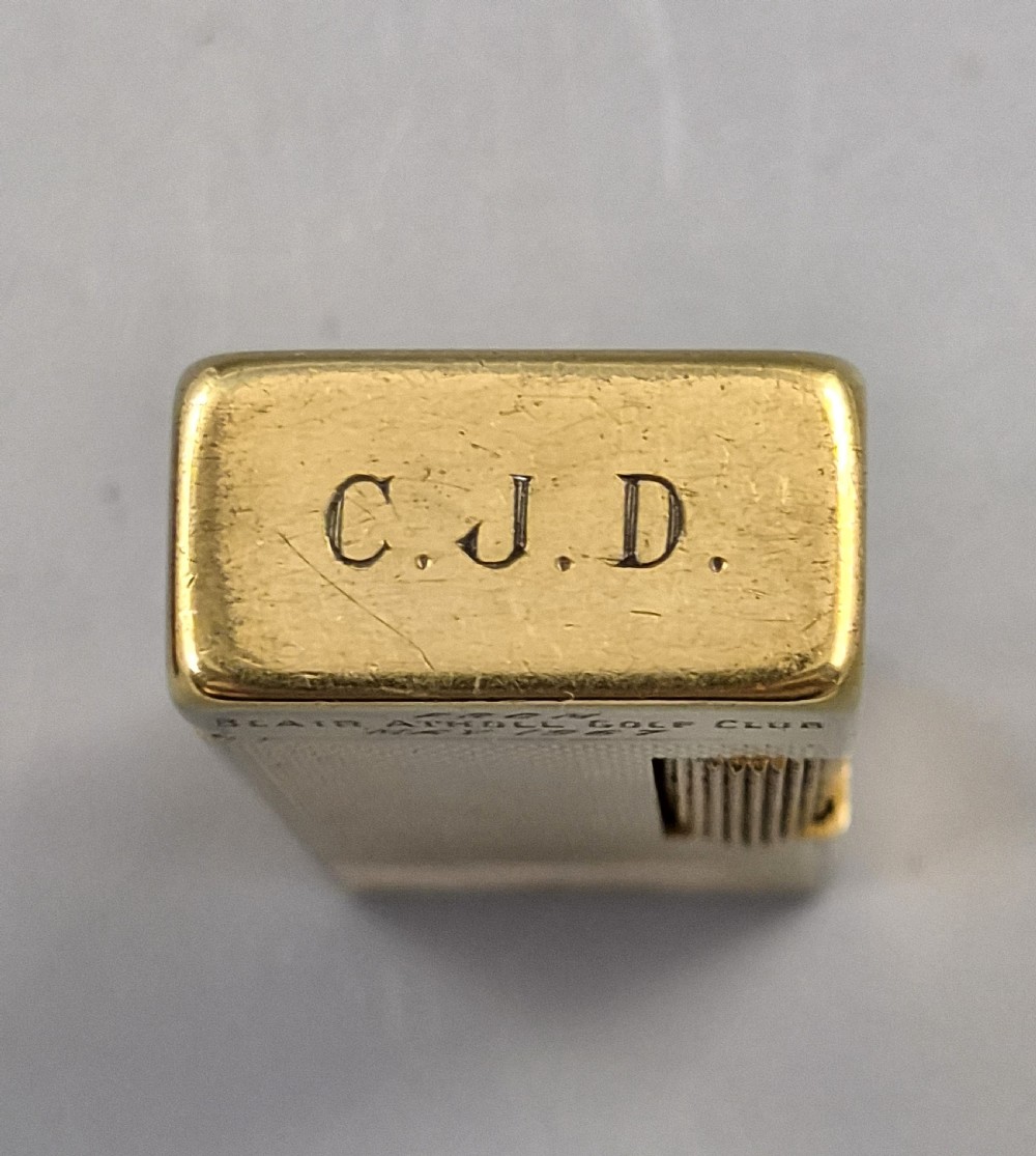 A 1967 gold-plated Dunhill Rollagas pocket lighter with a textured barley pattern, displayed alongside its fitted red presentation case and original printed instruction booklet. View V