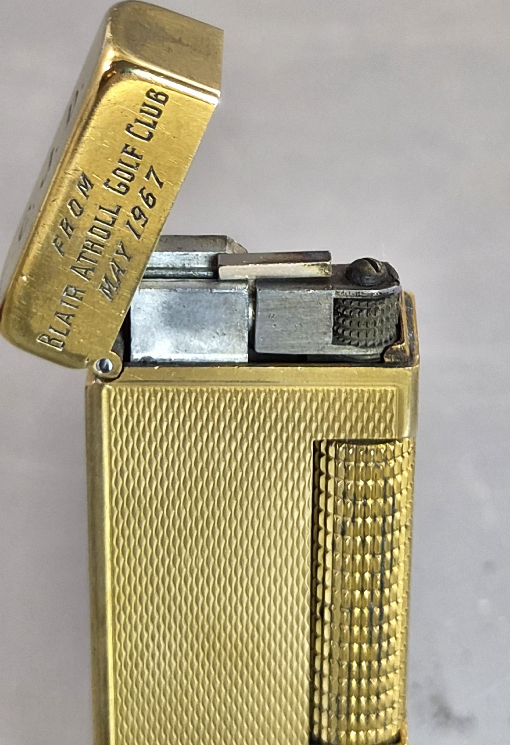 A 1967 gold-plated Dunhill Rollagas pocket lighter with a textured barley pattern, displayed alongside its fitted red presentation case and original printed instruction booklet. View VIII