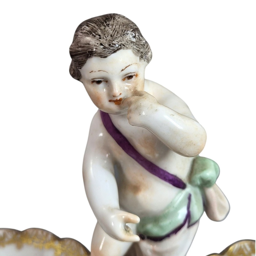 A 19th-century German hard-paste porcelain double salt cellar featuring a central sculpted figure of a cherub flanked by two shell-shaped bowls hand-painted with birds and insects. View XI