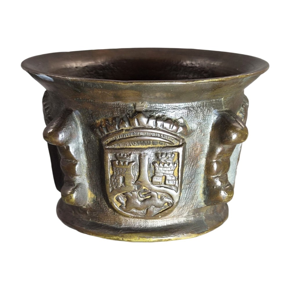 A heavy 17th-century cast bronze apothecary mortar featuring raised heraldic coat of arms motifs and side lugs around a flared rim. View VI