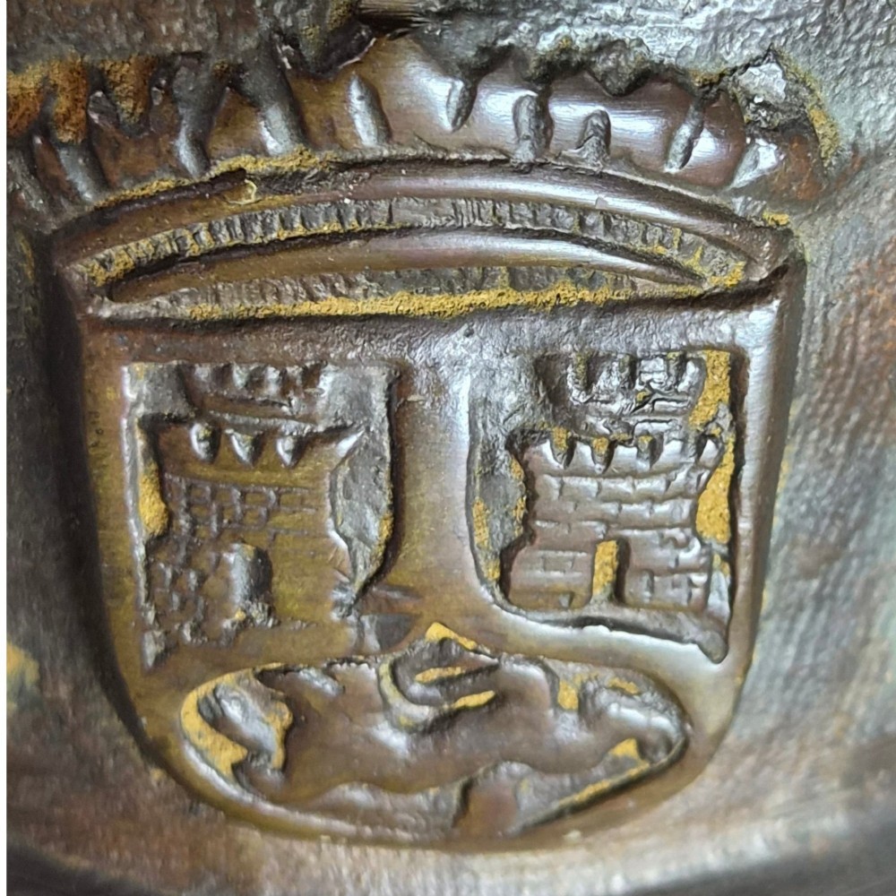 A heavy 17th-century cast bronze apothecary mortar featuring raised heraldic coat of arms motifs and side lugs around a flared rim. View VII