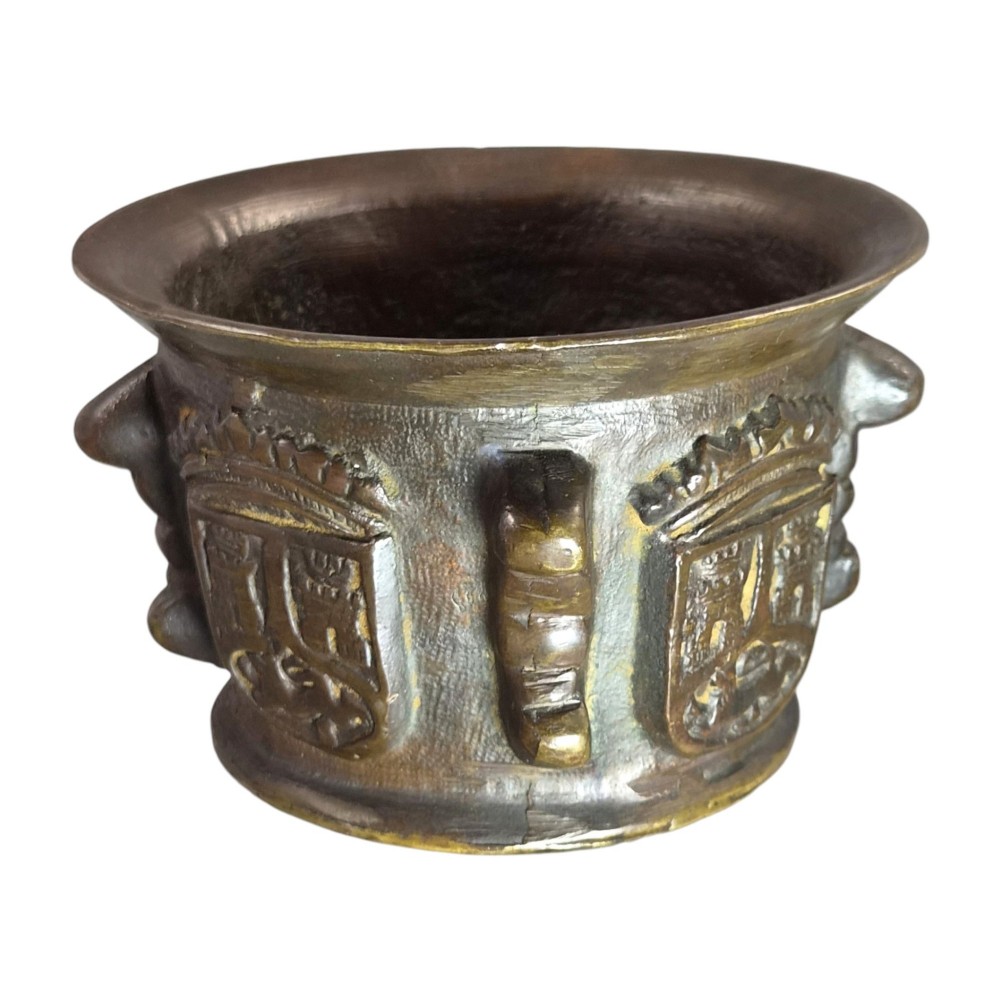 A heavy 17th-century cast bronze apothecary mortar featuring raised heraldic coat of arms motifs and side lugs around a flared rim. View VIII