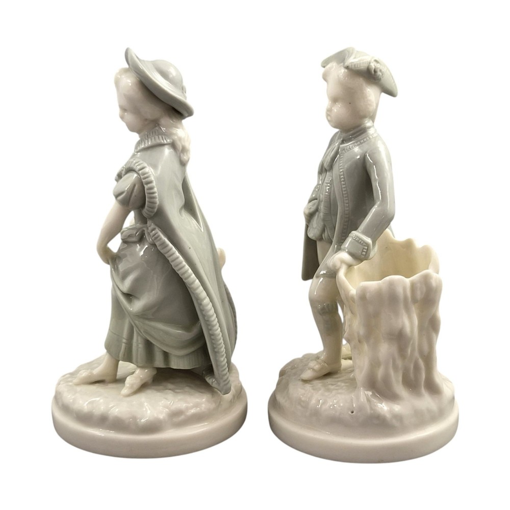 A pair of late Victorian grey and cream glazed porcelain figural salts depicting a man and woman beside hollow tree stump vessels. View II