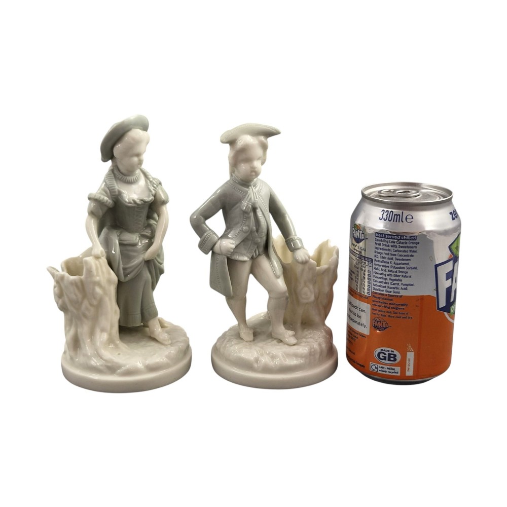 A pair of late Victorian grey and cream glazed porcelain figural salts depicting a man and woman beside hollow tree stump vessels. View V